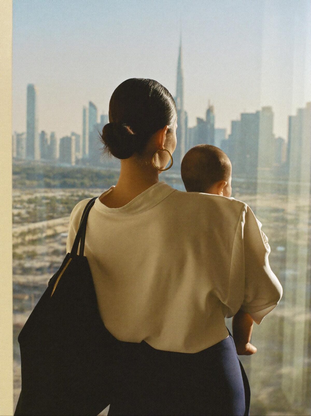 A mother holding her child, looking out over the Dubai skyline